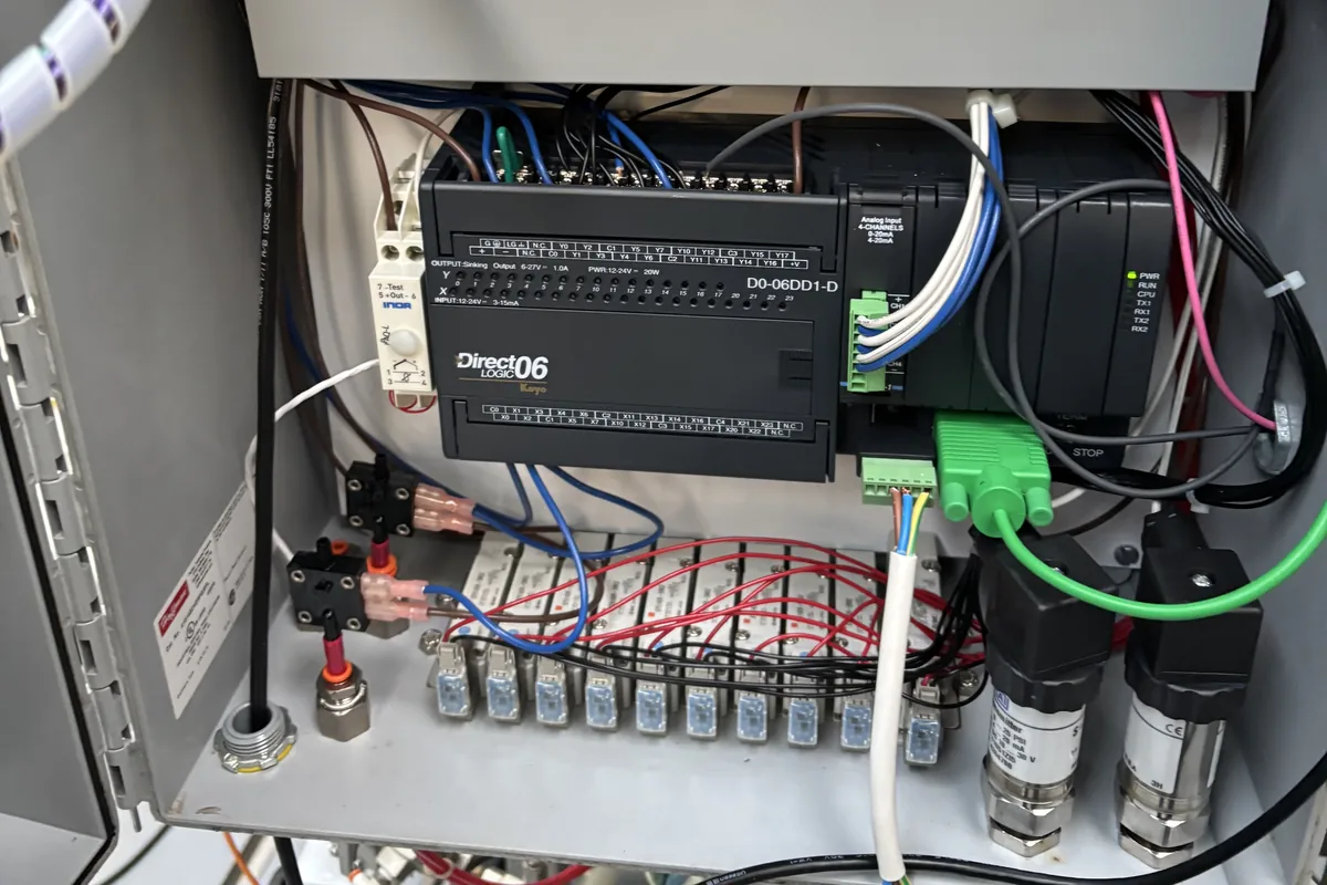 The open control cabinet of a Meheen bottling machine